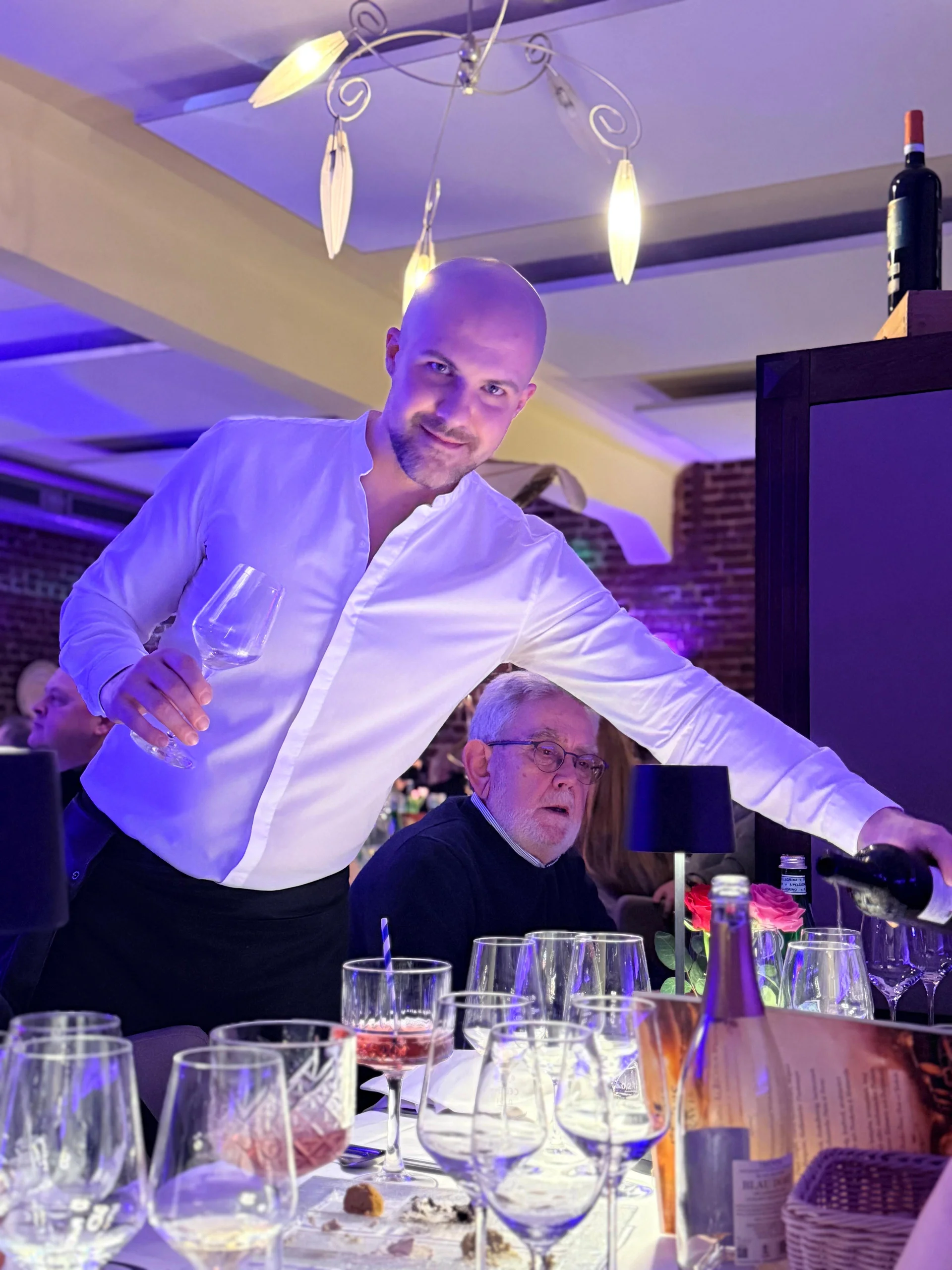 Kellner schenkt Rotwein am Tisch ein