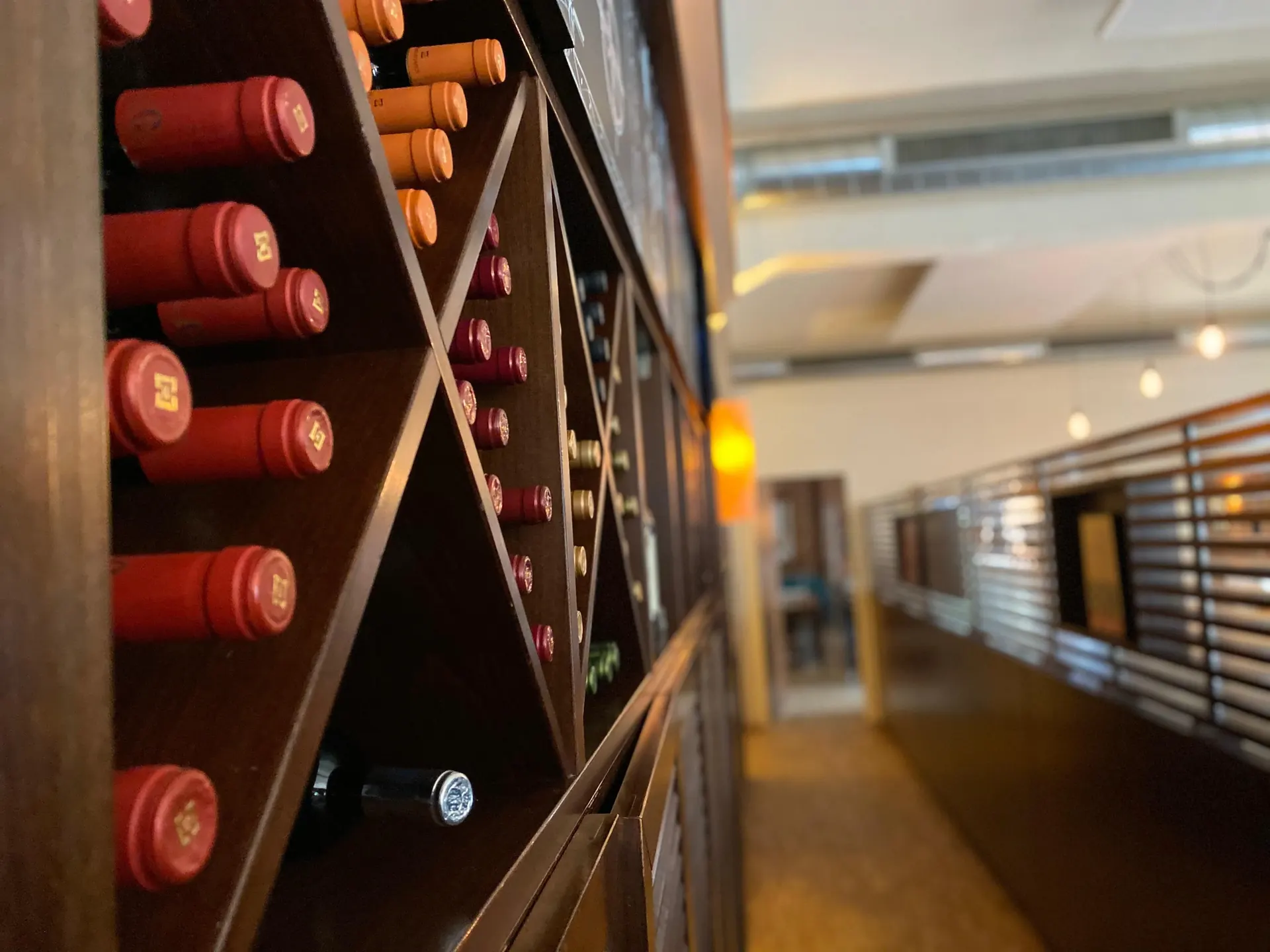 Erlesene Weinauswahl im beleuchteten Weinregal des Mama Mia